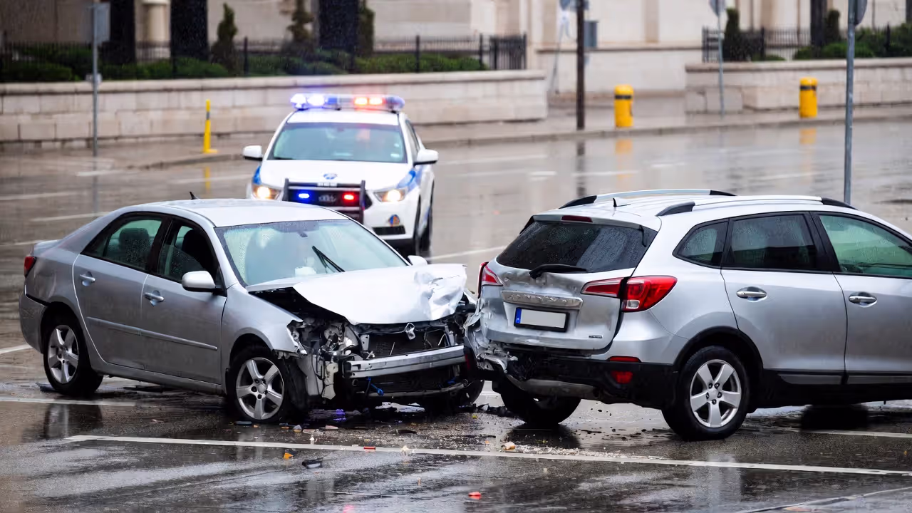 Damaged vehicles at intersection after collision with police car in background